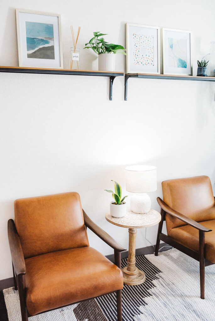 Vertical shot of brown chairs with white lamp and a house plant in a table